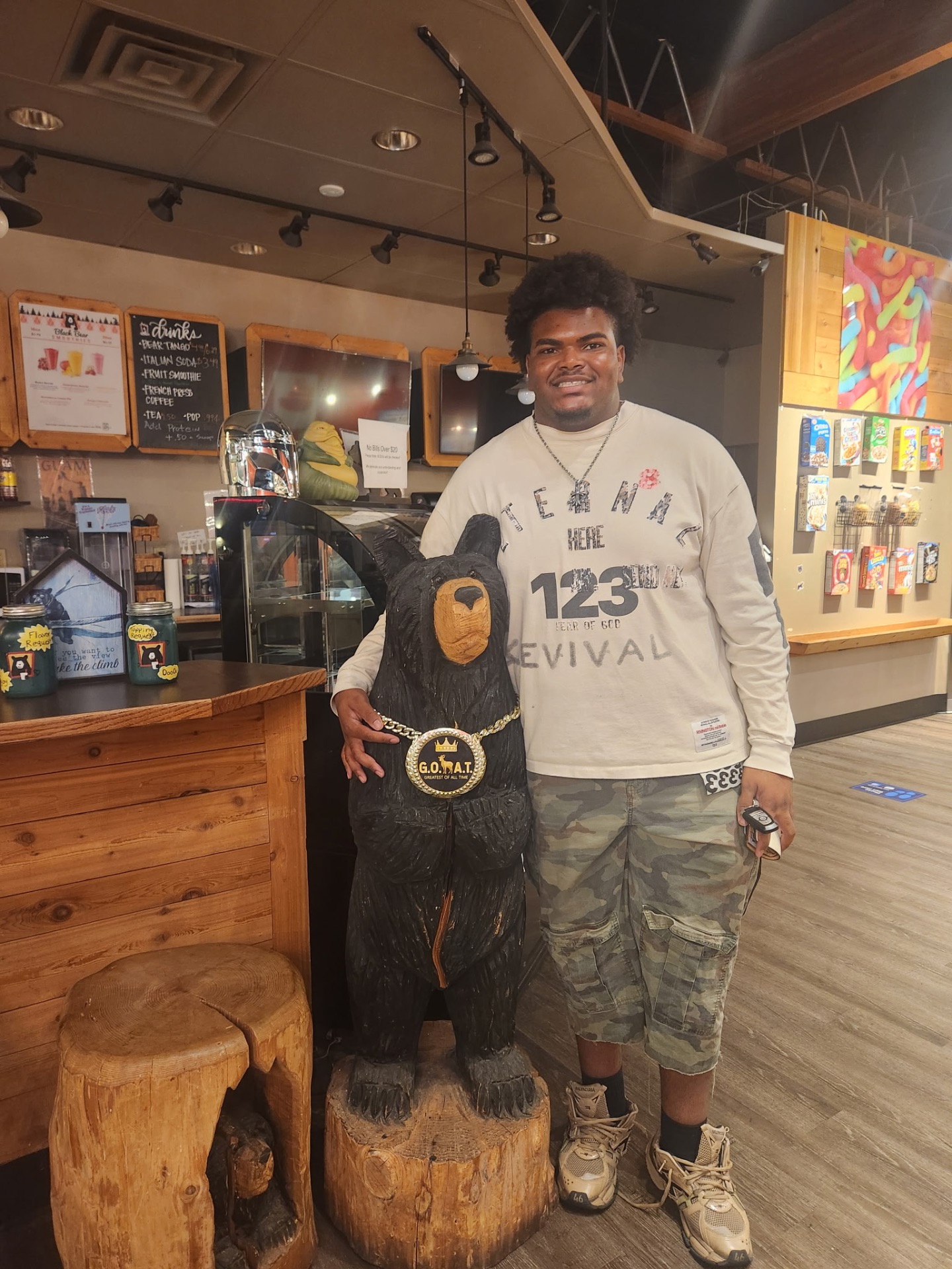 Guest posing with the G.O.A.T. carved bear inside the Black Bear shop