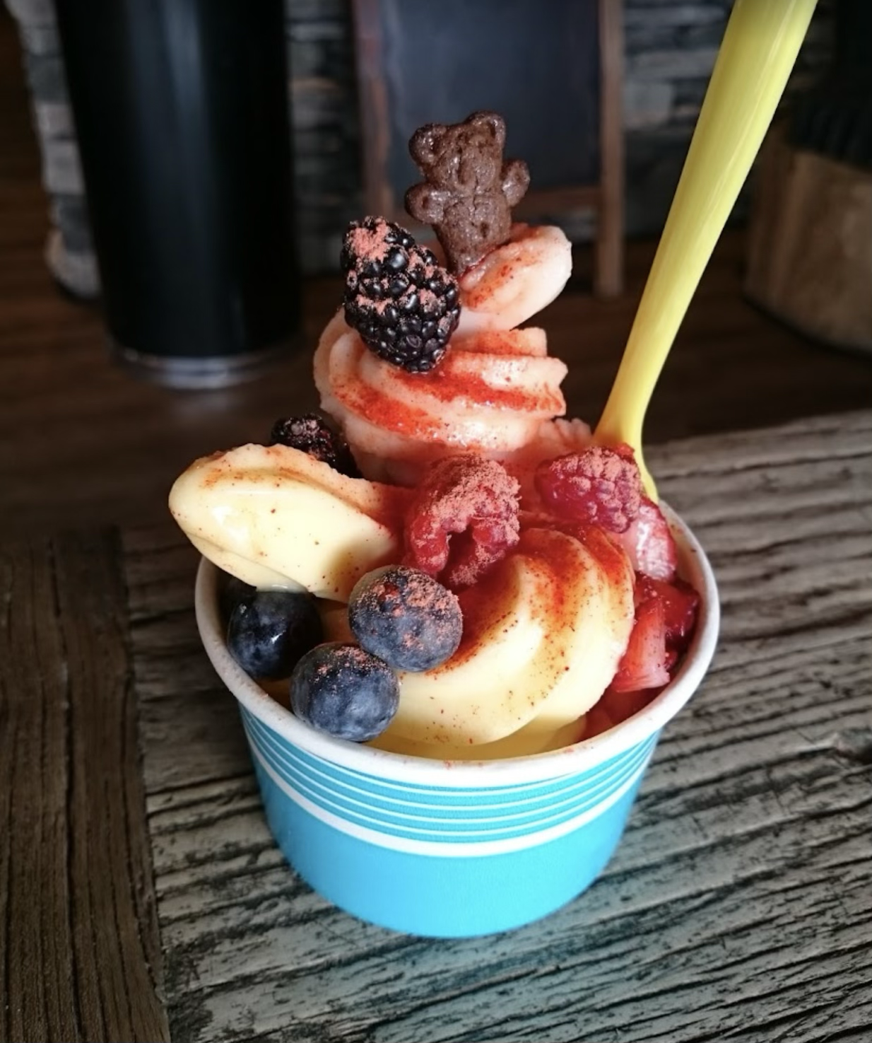 Frozen yogurt cup topped with fresh blackberries, blueberries and banana